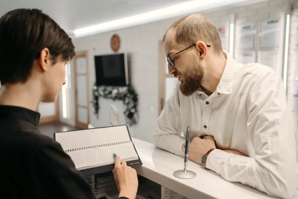 Una recepcionista enseña la agenda a un cliente